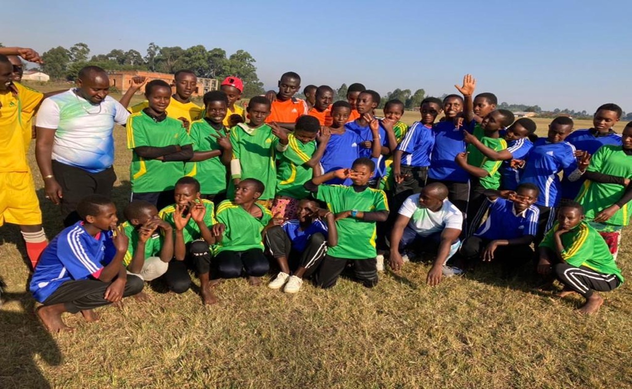 Young people in team jerseys and community members gathered on a field after a peace marathon